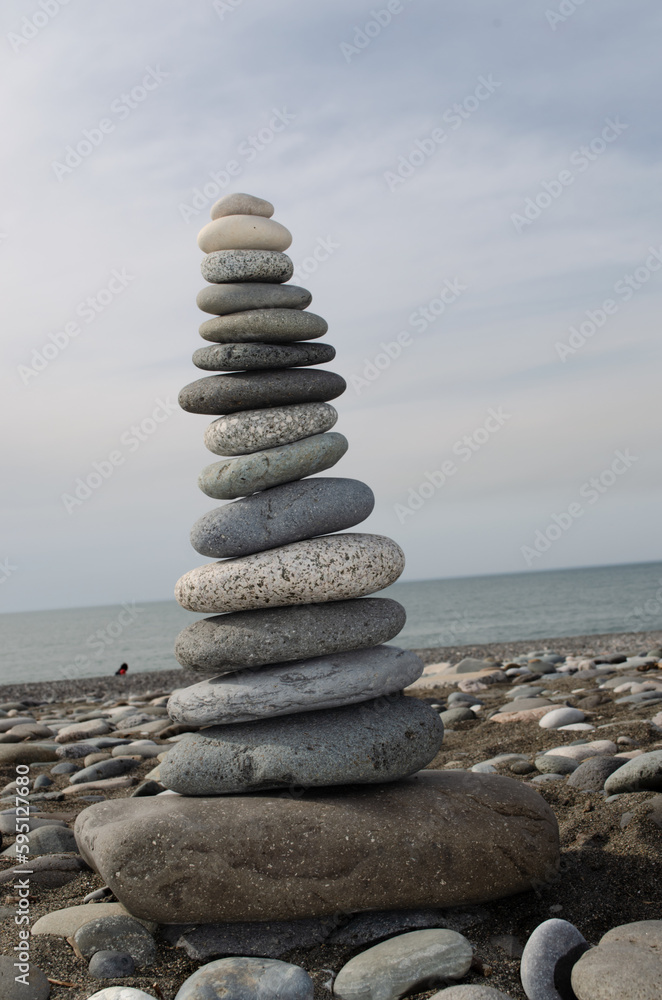 High cairn made of stones on a pebble beach, sea background. Stone's balance