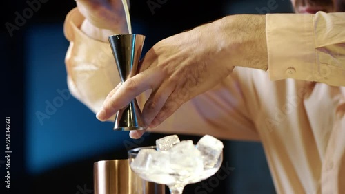Professional bartender masterly creating a cocktail in modern bar. Experienced barman adding syrip into shaker using jigger - food and drink photo