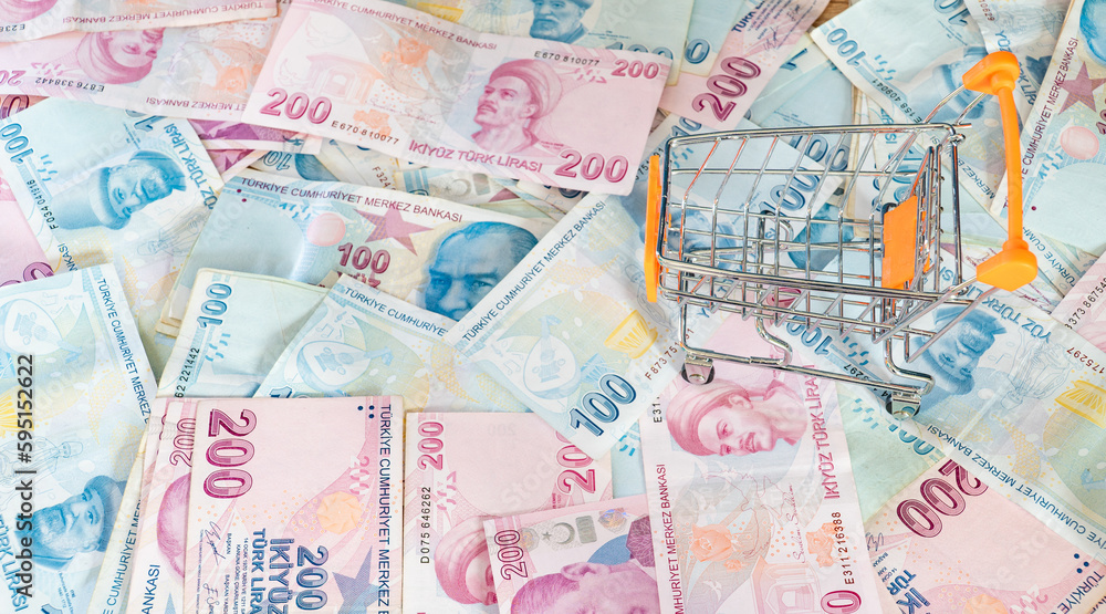 Obraz premium Cost of living concept. Empty cart on a stack of Turkish liras. Inflation rising in Turkey. Economic crisis. Rising costs in daily life