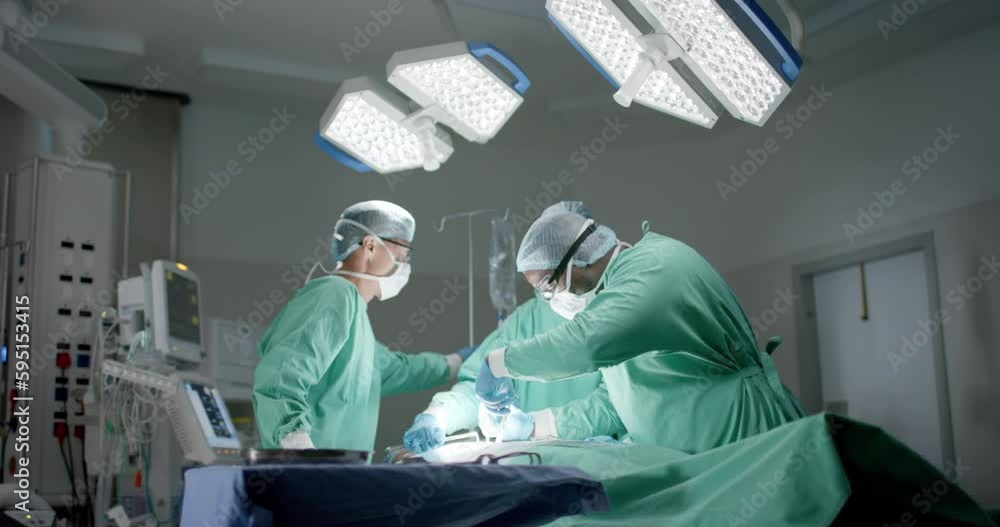 Diverse surgeons with face masks during surgery in operating room in slow motion Diverse surgeons with face masks during surgery in operating room in slow motion
