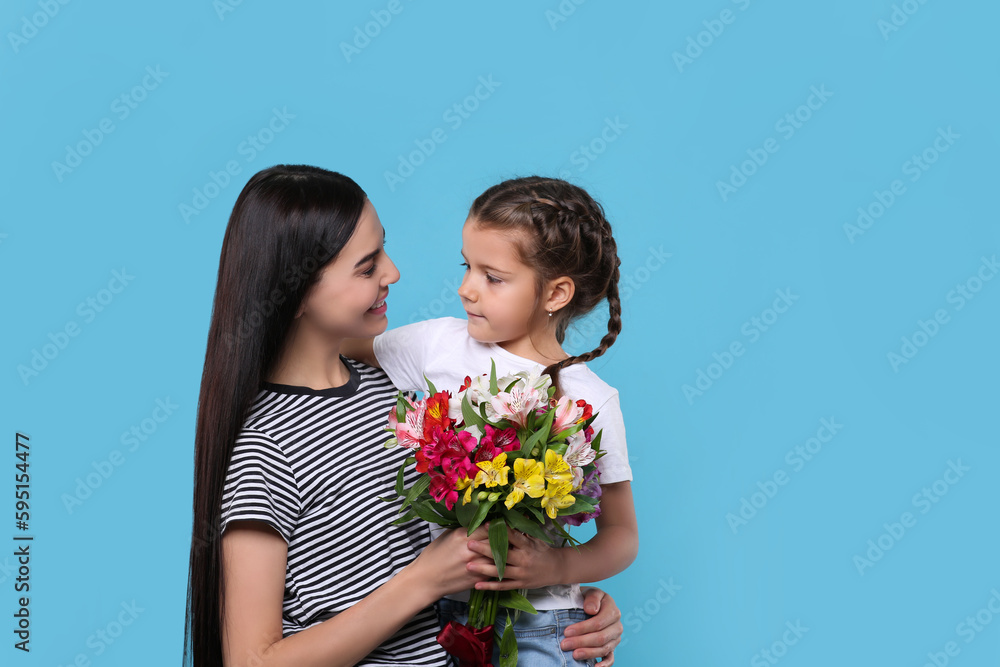 Happy woman with her daughter and bouquet of beautiful flowers on light blue background, space for text. Mother's day celebration Happy woman with her daughter and bouquet of beautiful flowers on light blue background, space for text. Mother's day celebration