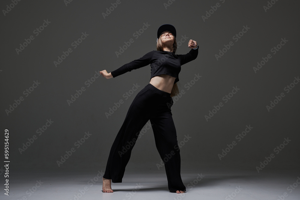 Obraz premium a girl in dark clothes dances and jumps on a dark background background modern dance