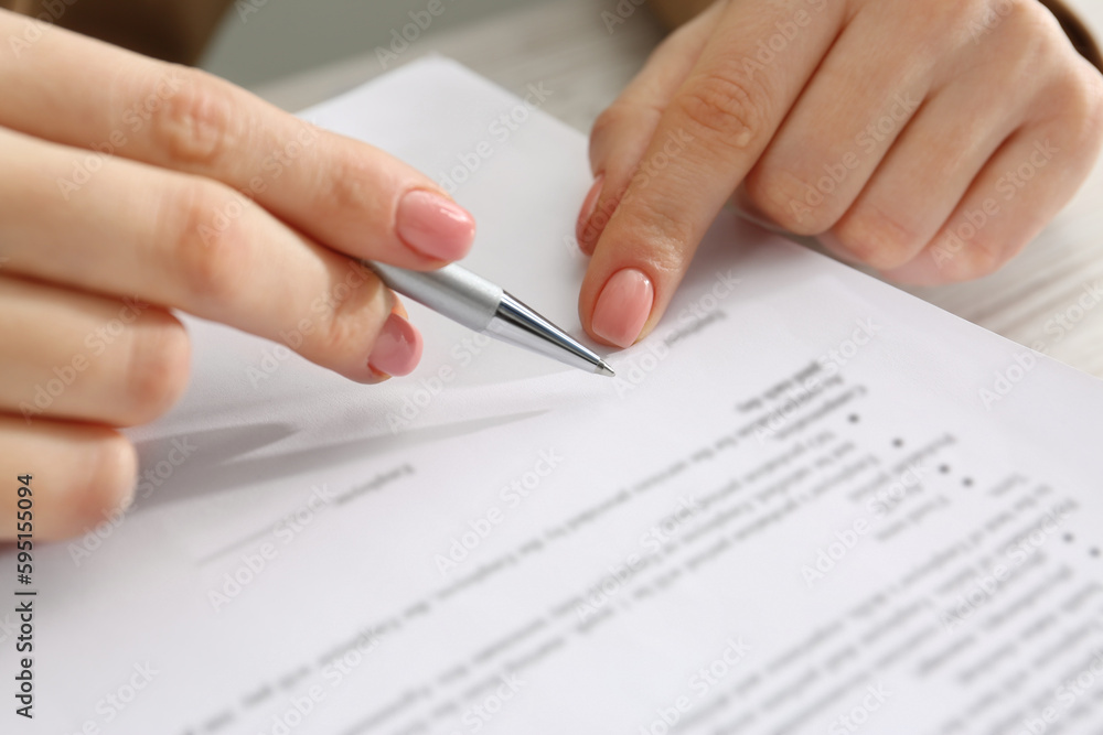 Woman signing document at table, closeup view Woman signing document at table, closeup view