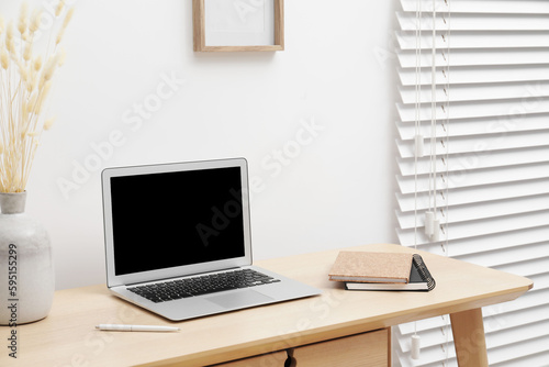 Cosy workspace with laptop and stationery on desk at home