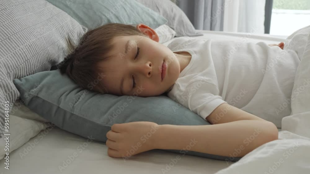 Portrait of little boy sleeping in bed at morning. Modern bedroom with big window Portrait of little boy sleeping in bed at morning. Modern bedroom with big window
