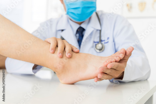 The orthopedic doctor or surgeon in white gown examined the patient with foot pain problem.White clean table or bed with blur background.Hallux or bunion with transfer metatarsalgia.Orthopaedic unit. © Issara