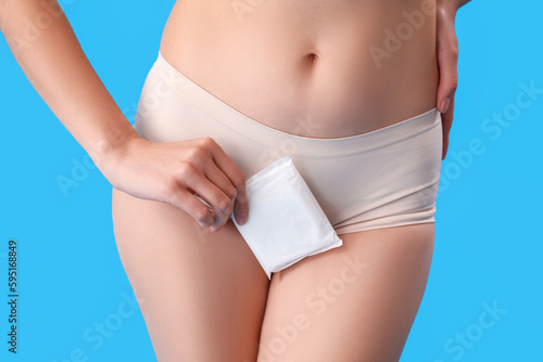 Young woman in menstrual panties with pad on blue background, closeup © Pixel-Shot