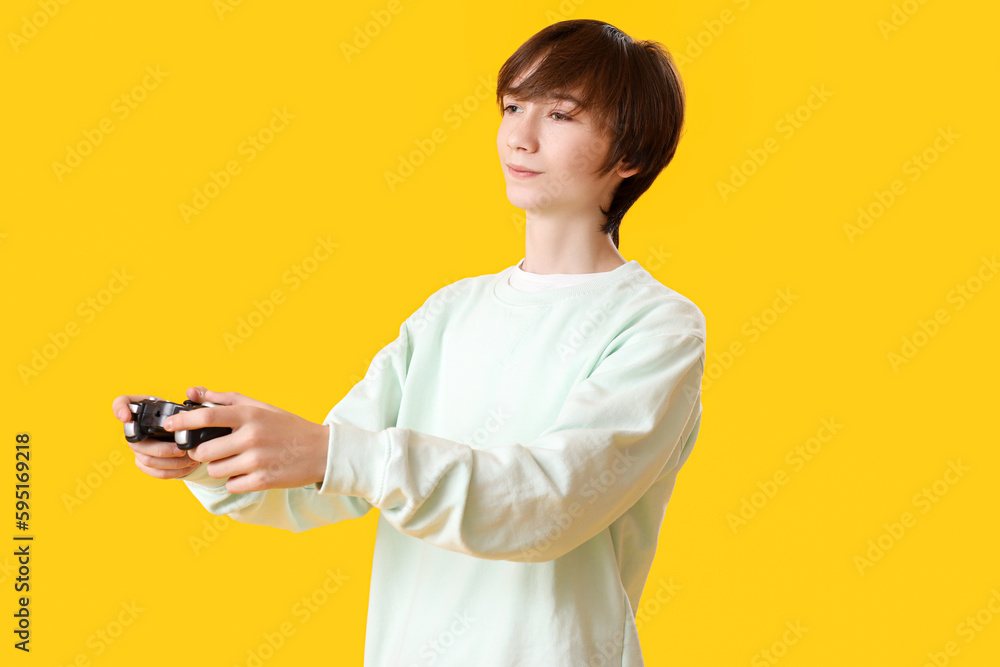 Teenage boy with game pad on yellow background Teenage boy with game pad on yellow background