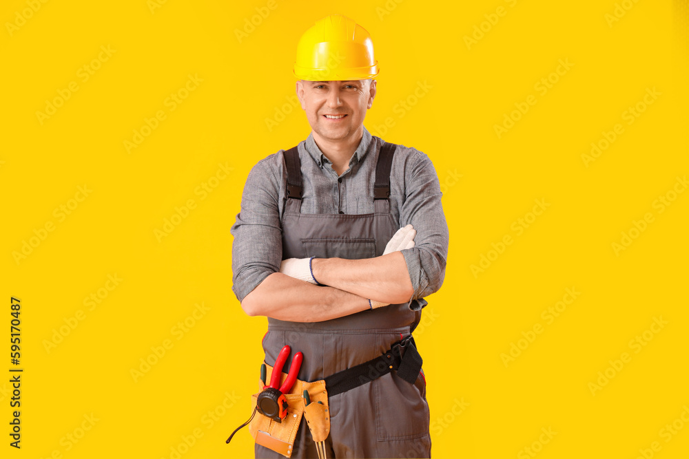 Mature carpenter in hardhat on yellow background Mature carpenter in hardhat on yellow background