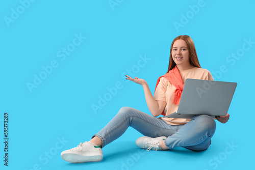 Female programmer with laptop showing something on blue background © Pixel-Shot