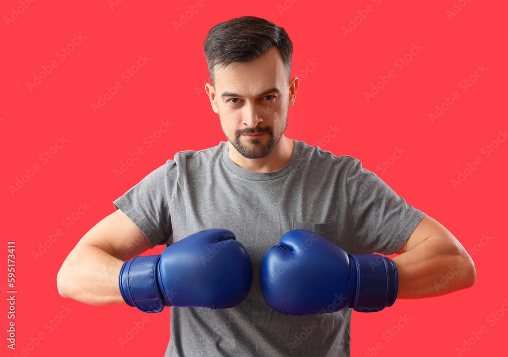 Sporty young man in boxing gloves on red background Sporty young man in boxing gloves on red background