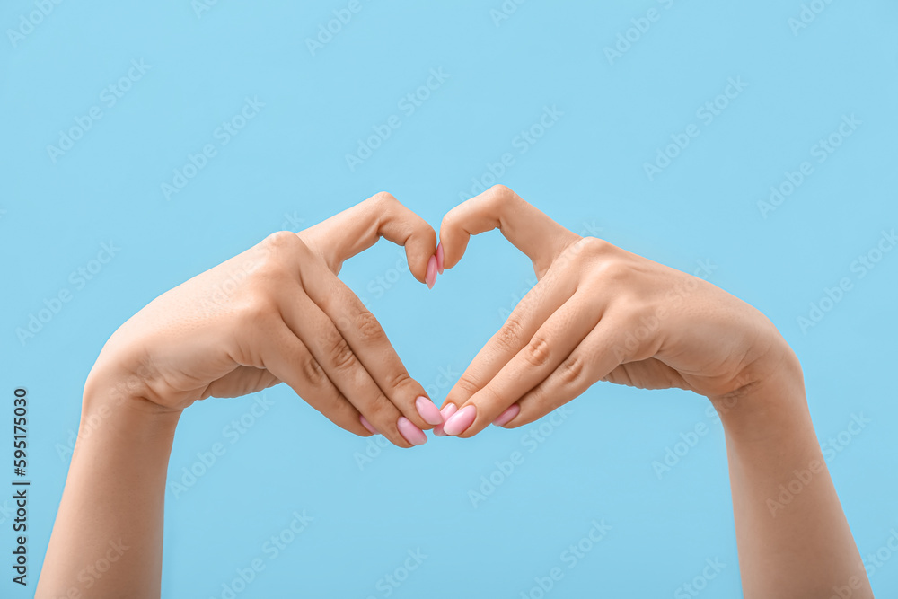 Woman making heart with her hands on blue background