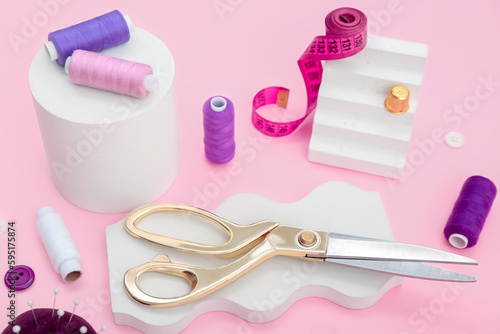 Podiums with tailor's supplies on pink background