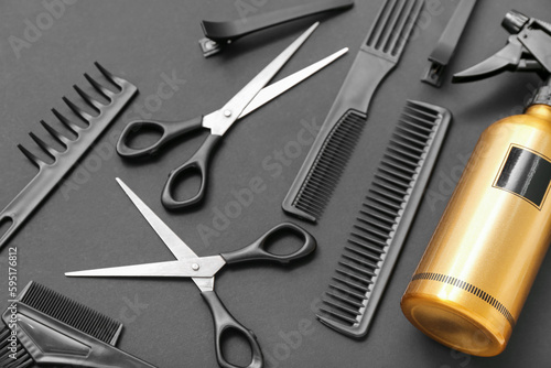 Composition with hairdressing accessories and spray bottle on black background, closeup