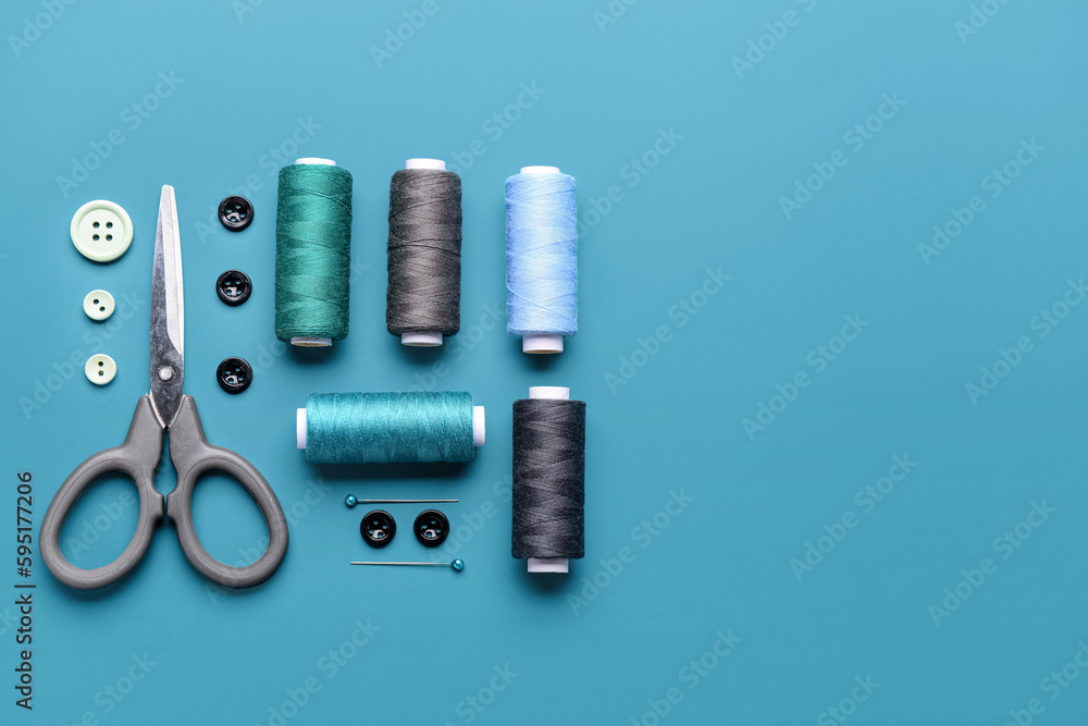 Fototapeta premium Composition with thread spools, buttons and scissors on color background