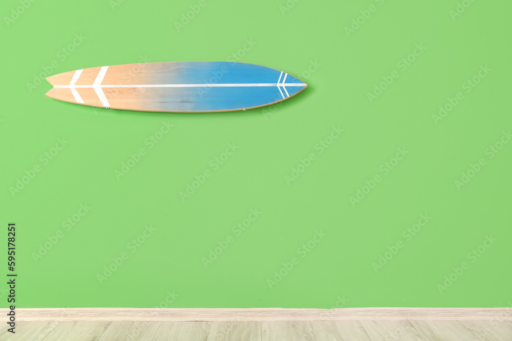 Wooden surfboard hanging on green wall in room Wooden surfboard hanging on green wall in room