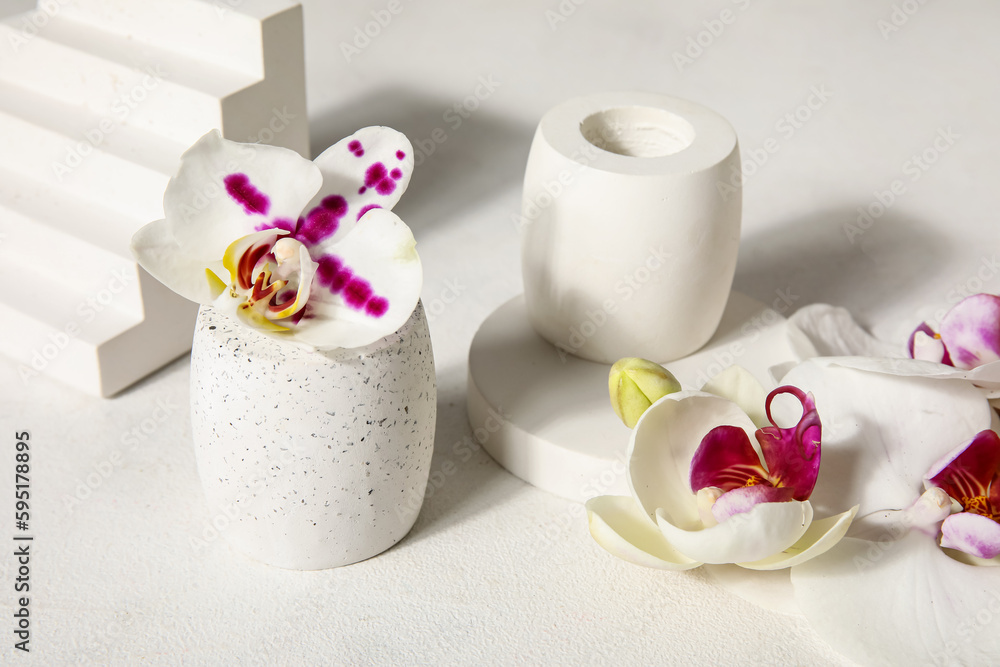 Decorative plaster podiums and beautiful orchid flowers on white table, closeup Decorative plaster podiums and beautiful orchid flowers on white table, closeup