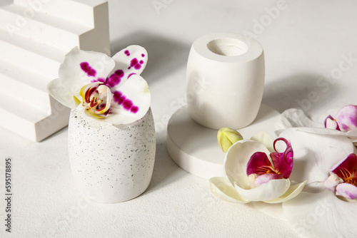 Decorative plaster podiums and beautiful orchid flowers on white table, closeup