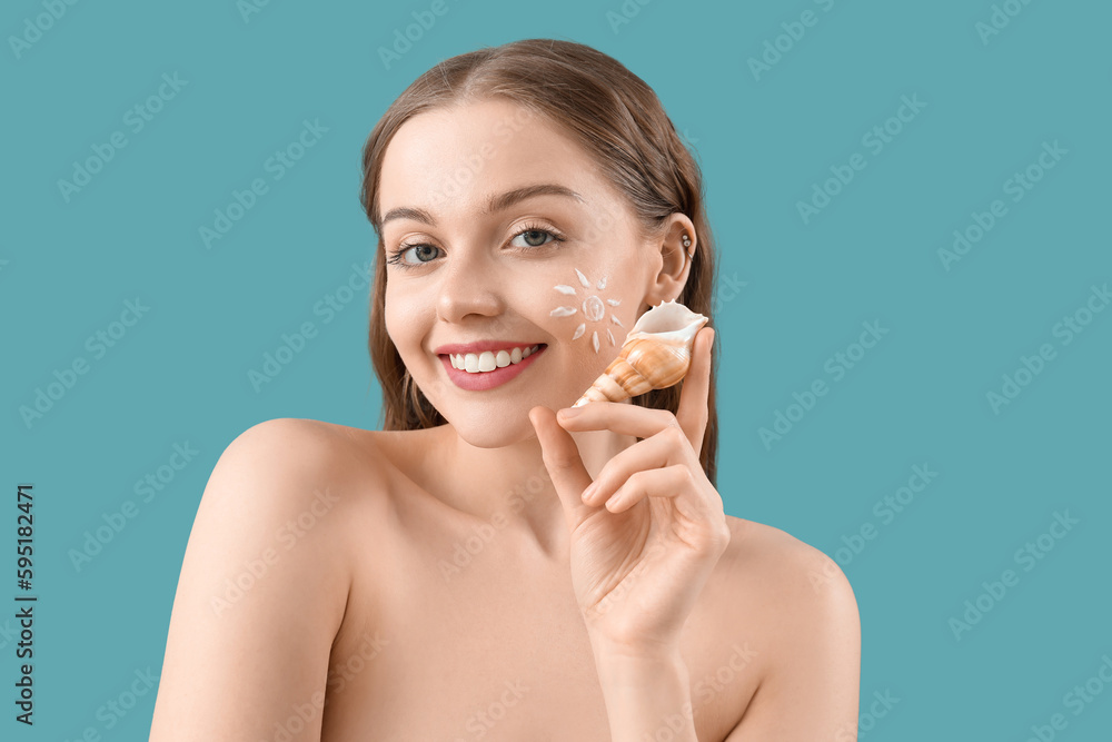Beautiful naked young woman with sunscreen cream on her face and sea shell against blue background Beautiful naked young woman with sunscreen cream on her face and sea shell against blue background