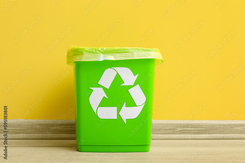 Trash bin with recycling symbol near yellow wall Trash bin with recycling symbol near yellow wall