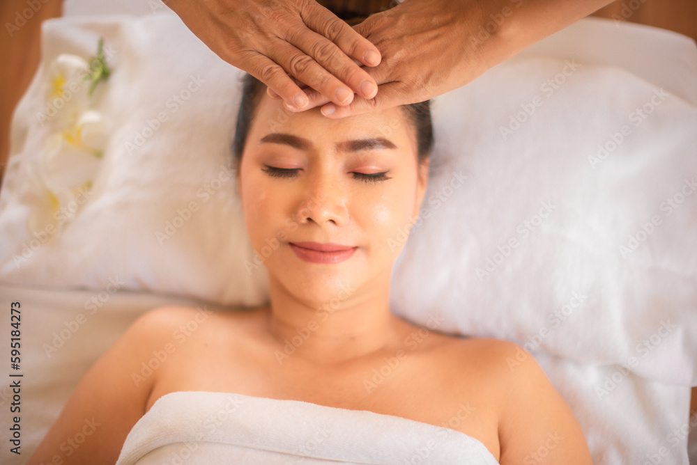 Beautiful asian woman being massaged with smile on her face by professional masseuse hands on white bed. Beautiful asian woman being massaged with smile on her face by professional masseuse hands on white bed.