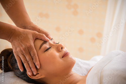 Beautiful asian woman being massaged with smile on her face by professional masseuse hands. © Digital Art Studio