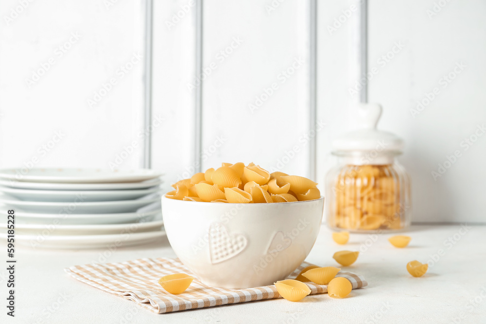 Bowl with raw conchiglie pasta on light background Bowl with raw conchiglie pasta on light background