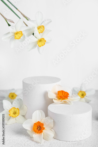 Decorative plaster podiums with flowers on grunge table against white background
