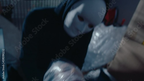 Female victim suffocating with head wrapped in plastic bag, being strangled by murderer in mask and hoodie, crime scene in dark garage. Handheld camera shot