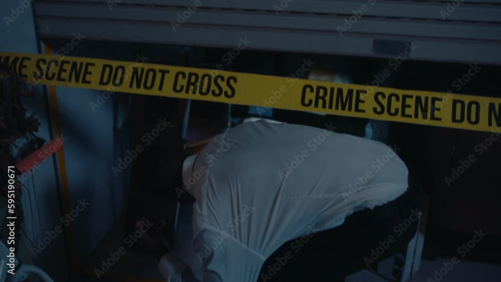 Male investigator walking with flashlight to crime scene, going under