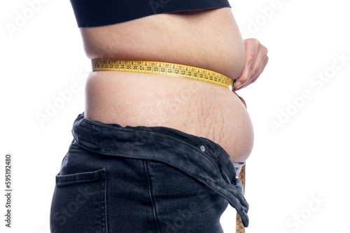 A woman with fat on her stomach measures the volume with a measuring tape. Overweight and diet. Without background.
