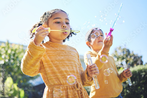 Playing, garden and children blowing bubbles for bonding, weekend activity and fun together. Recreation, outdoors and siblings with a bubble toy for leisure, childhood and enjoyment in summer