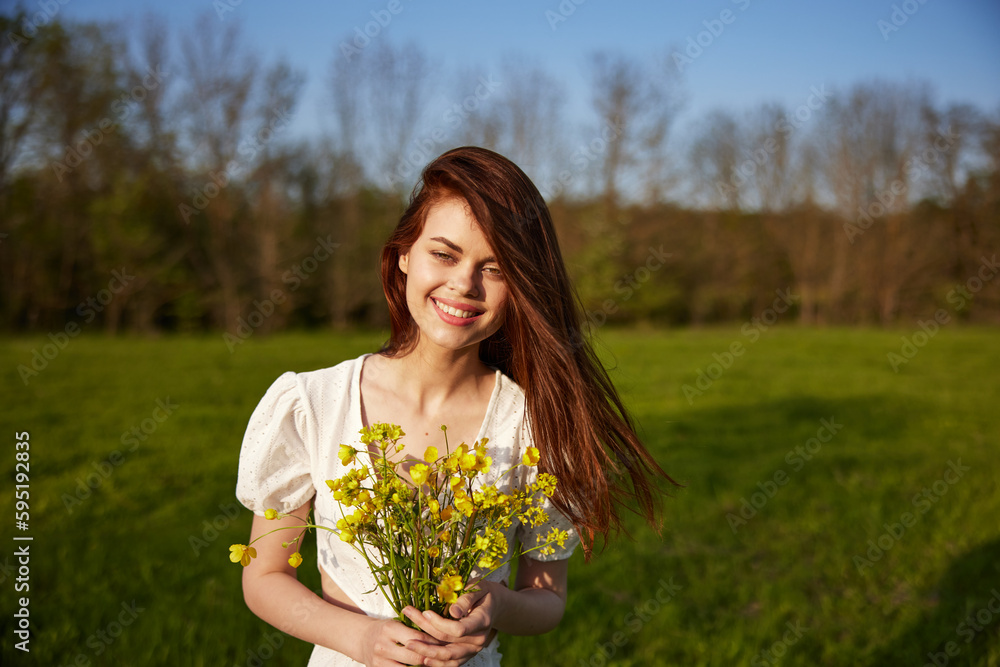 Beautiful woman in a white dress with a bouquet of yellow wildflowers walking in a field Beautiful woman in a white dress with a bouquet of yellow wildflowers walking in a field