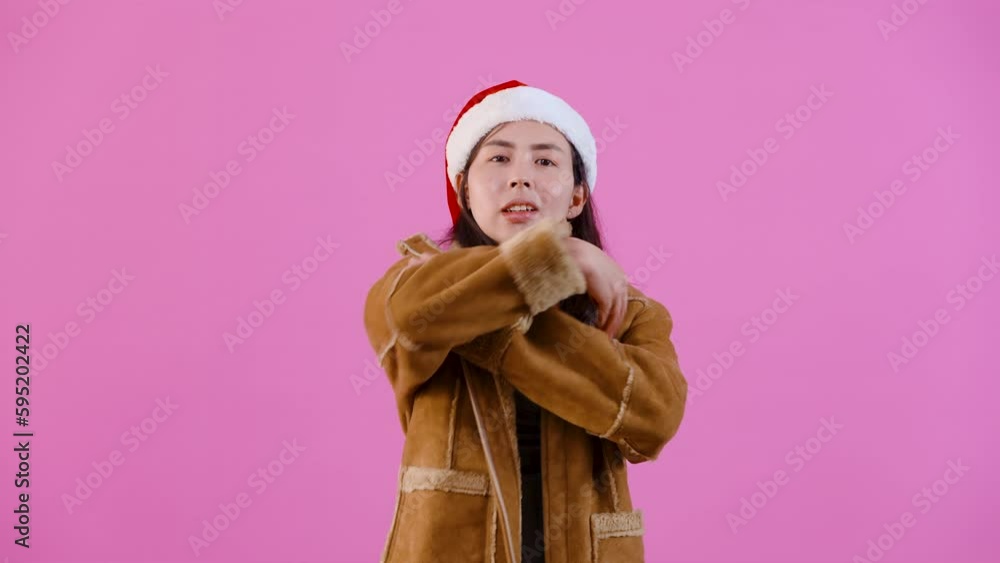 4K, Beautiful Asian girl in long-sleeved shirt wearing Christmas hat, was putting both his hands on his chest, his expression tense, frustrated by something, Isolated indoor studio on pink background. 4K, Beautiful Asian girl in long-sleeved shirt wearing Christmas hat, was putting both his hands on his chest, his expression tense, frustrated by something, Isolated indoor studio on pink background.