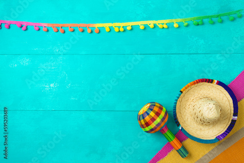 Mexican party decorations with sombrero hat and maracas on blue wooden background. Cinco de Mayo holiday celebration. Top view from above