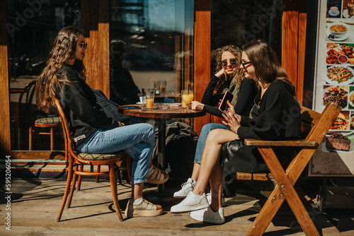 Three happy girls sitting at the coffee bar and having fun conversation
