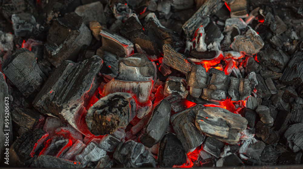Obraz premium Burning charcoal for grilling close-up. Smoldering charcoal inside the grill gives heat for cooking pickled meat, barbecue, steak, vegetables, barbecue.