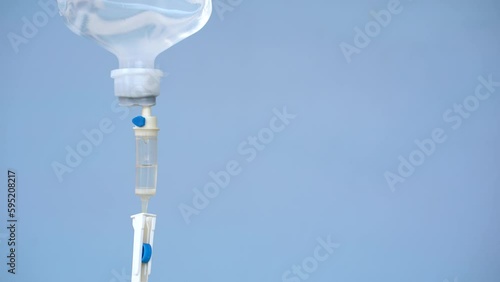 Closeup of IV loading dose in hospital with blue background, Intravenous saline solution.