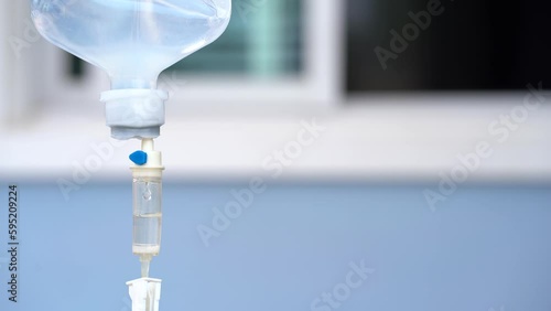 Closeup of IV in hospital with blue background, Intravenous saline solution.