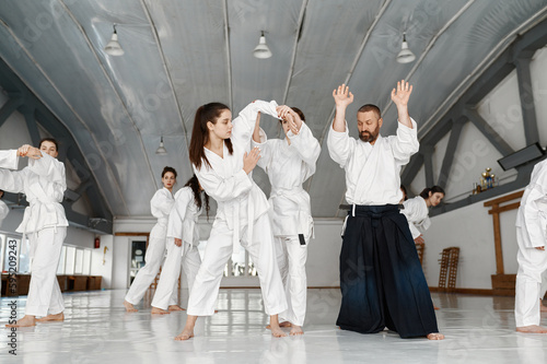 Teenage girls group of students having aikido fight under instructor control