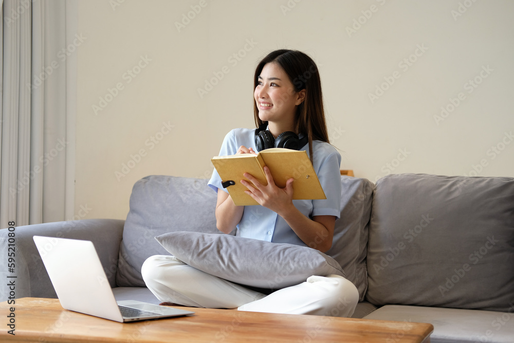 Portrait of young beautiful asian woman relax holding book listen to music from headphone in bedroom. Smile happy asian girl relaxing knowledge education university lifestyle, back to school concept Portrait of young beautiful asian woman relax holding book listen to music from headphone in bedroom. Smile happy asian girl relaxing knowledge education university lifestyle, back to school concept