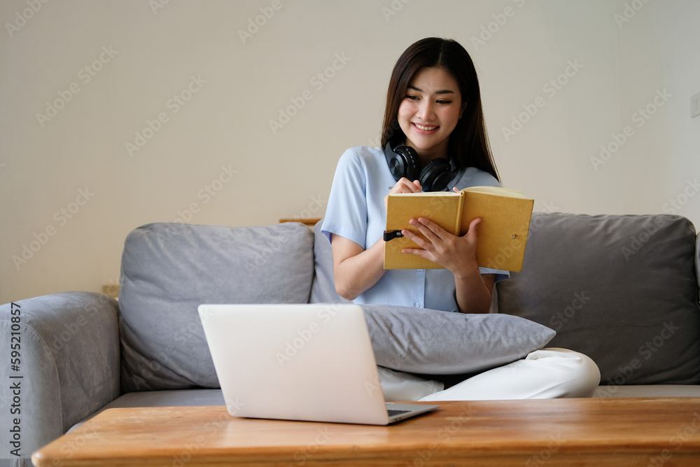 Focused asian woman taking notes while working remotely Focused asian woman taking notes while working remotely