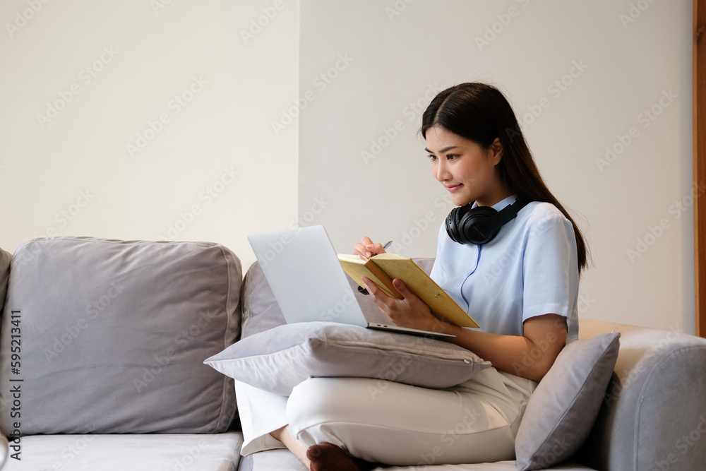 young woman browse internet noting something relaxing on sofa young woman browse internet noting something relaxing on sofa