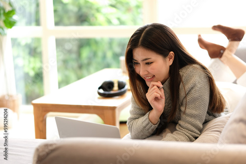attractive smart asian female adult long black hair working hand use laptop device working online from home at living room on the floor with cheerful freshness expression casual happiness lifestyle