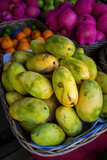 Close up on a basket full of ripe mangoes at a fruit market.