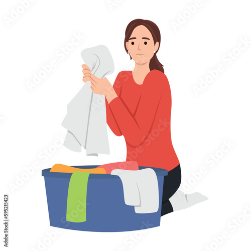 Young woman doing housework chores sorting dirty laundry in clothes basin
