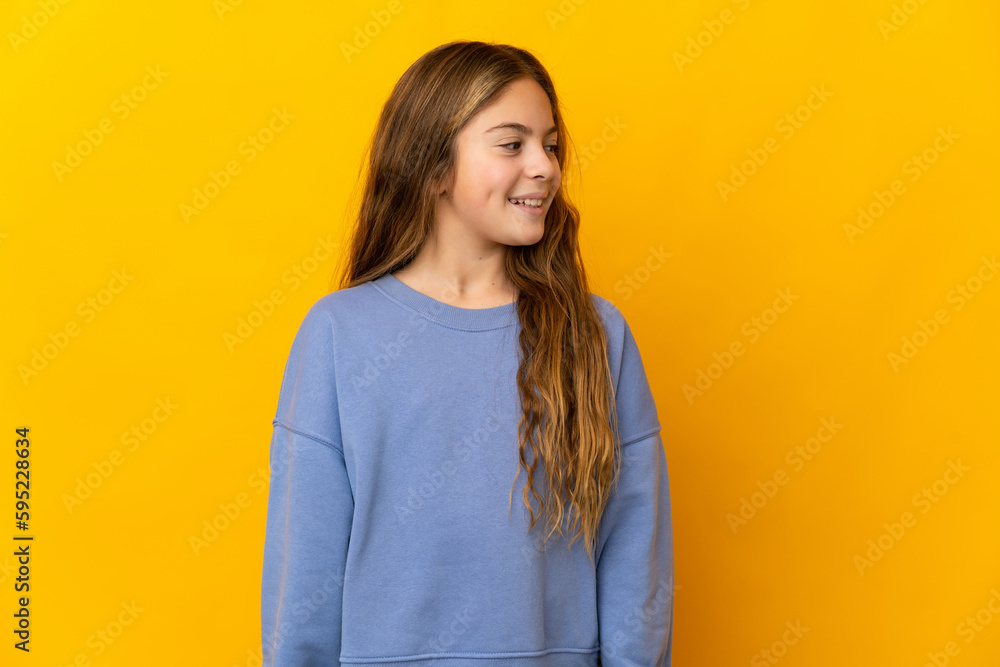 Child over isolated yellow background looking to the side and smiling Child over isolated yellow background looking to the side and smiling
