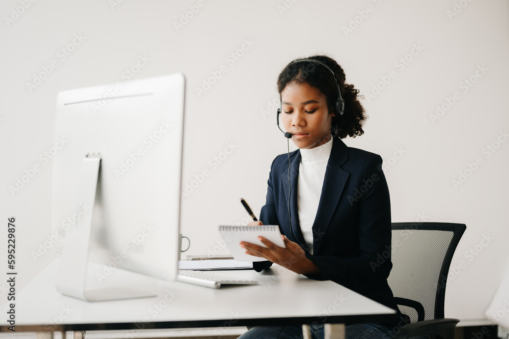Serious call center operator in wireless headset talking with customer, woman in headphones with microphone consulting client on phone in customer support service in business center Serious call center operator in wireless headset talking with customer, woman in headphones with microphone consulting client on phone in customer support service in business center