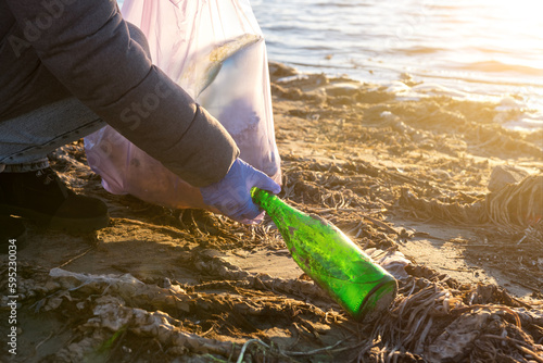 empty bottle on the beach. volunteers clean up trash on Earth Day. soft focus