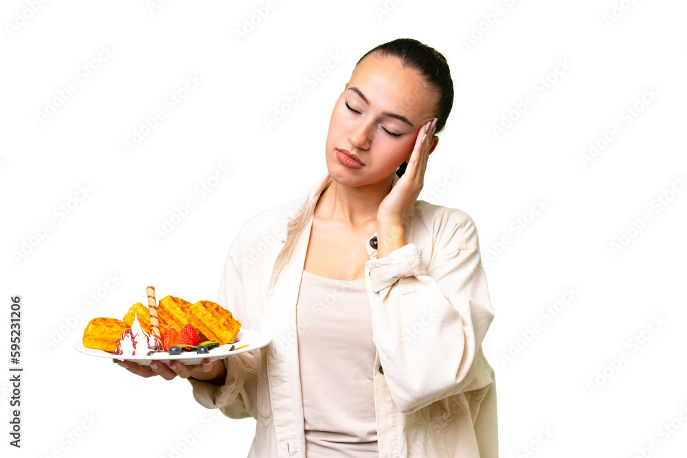 Young Arab woman holding waffles over isolated background with headache Young Arab woman holding waffles over isolated background with headache
